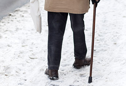 senior citizen using icespikes to prevent slipping on ice while walking
